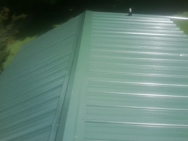 New green metal panels meeting at the ridge of a roof — Flat Roof Repair work by our crew in Meadow Valley