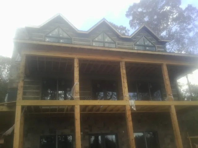 Dormers and porch framing on a large log home under construction — Roof Coating work by our crew in Meadow Valley