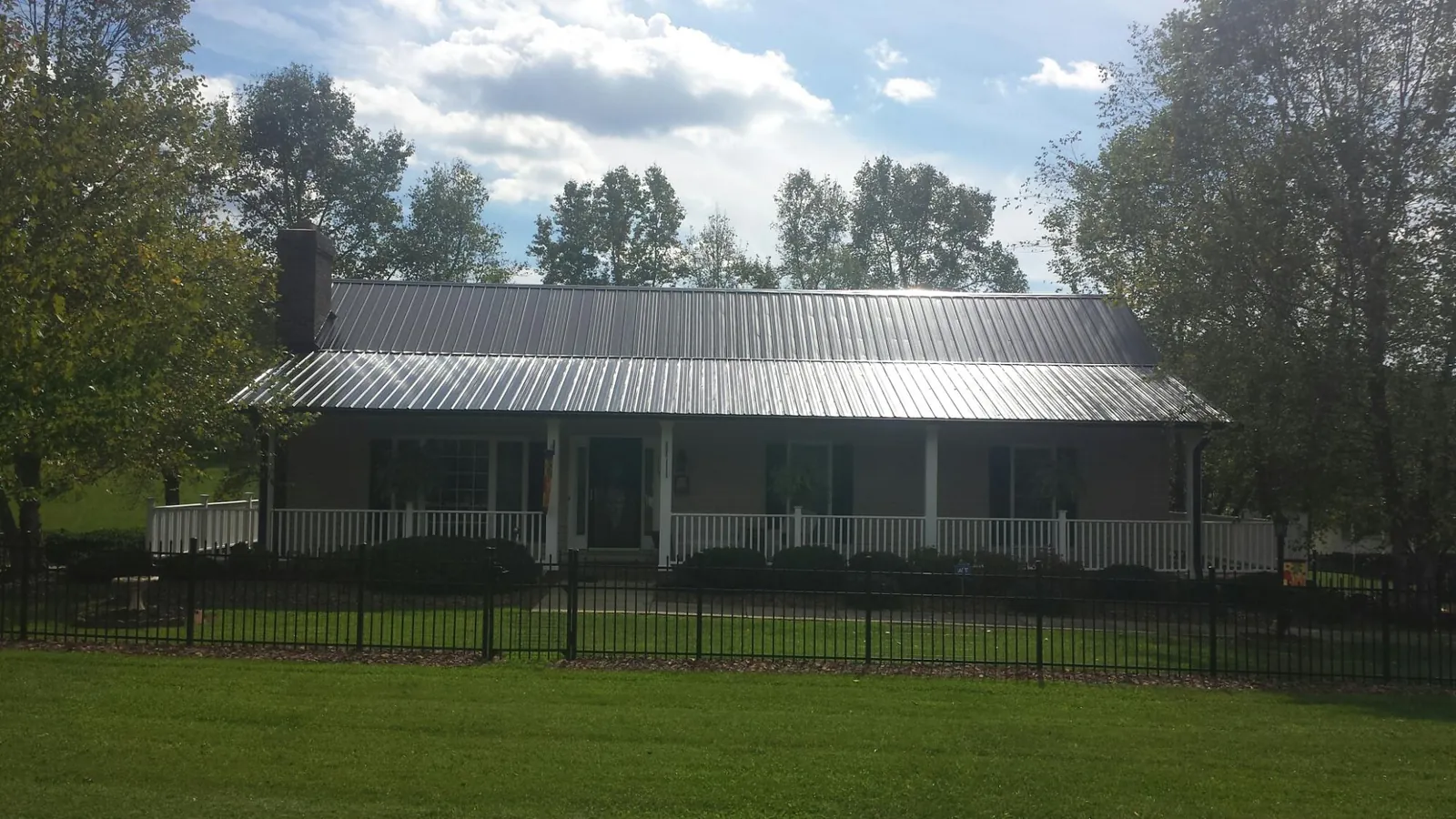 Gray metal roof on a brick ranch with a full width front porch — Gutter Guard Installation work by our crew in Meadow Valley