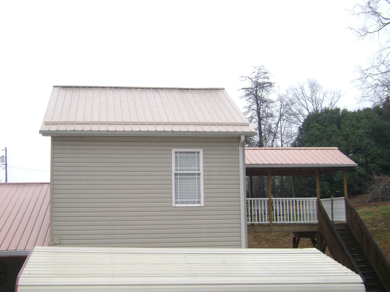 Tan metal roofs on a two story addition and attached porch, from a Roof Replacement job in Meadow Valley