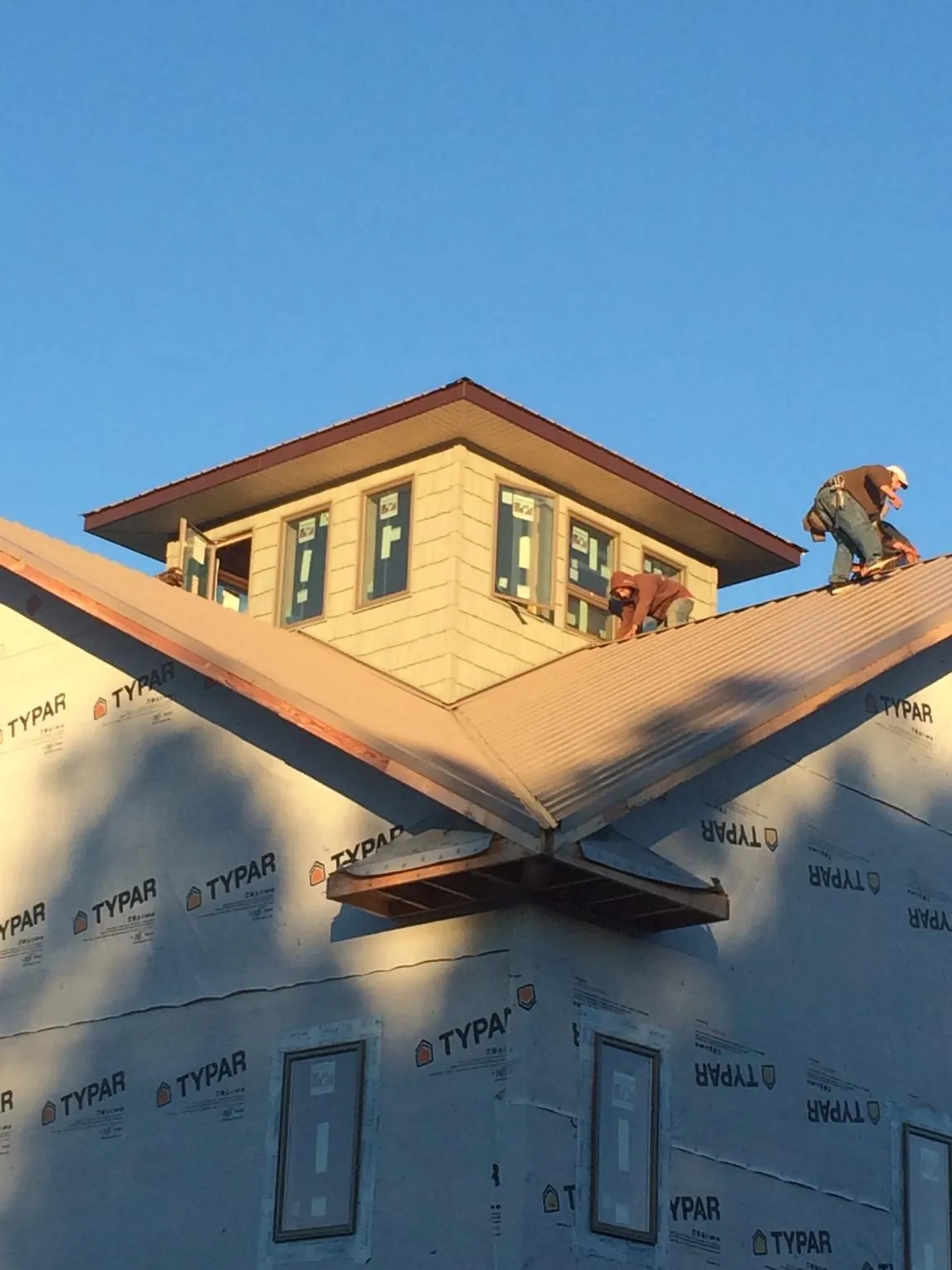 Roofers working around a rooftop cupola on a new metal roof at sunset — Roof Waterproofing in Meadow Valley by Roofing Brothers
